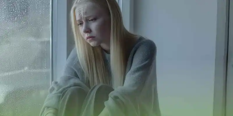 Девушка с тревожно-депрессивным расстройством сидит у окна